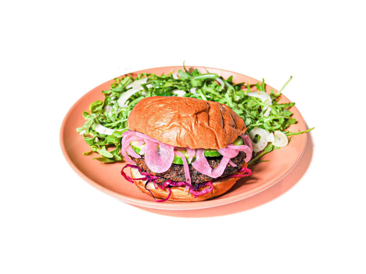 NomNom Burger's Signature Falafel Burger features a crispy, golden falafel patty, topped with tangy pickled onions and marinated cabbage. This flavorful combination delivers a refreshing, vibrant twist on a classic burger, perfect for a delightful and satisfying plant-based meal.