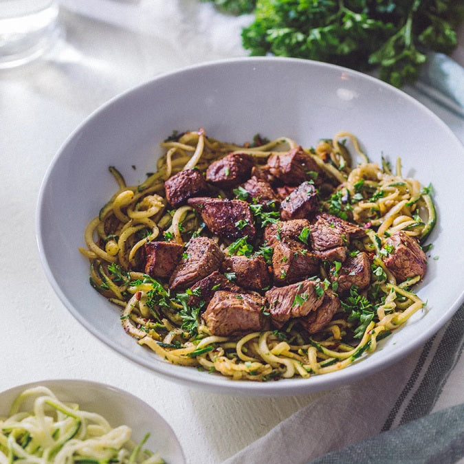 SF Noodle Bar's Steak Bites and Baby Bok Choy features tender, savory steak bites paired with crisp, fresh baby bok choy over a bed of fragrant garlic noodles. This dish brings together hearty and vibrant flavors, perfect for a satisfying and delicious meal.