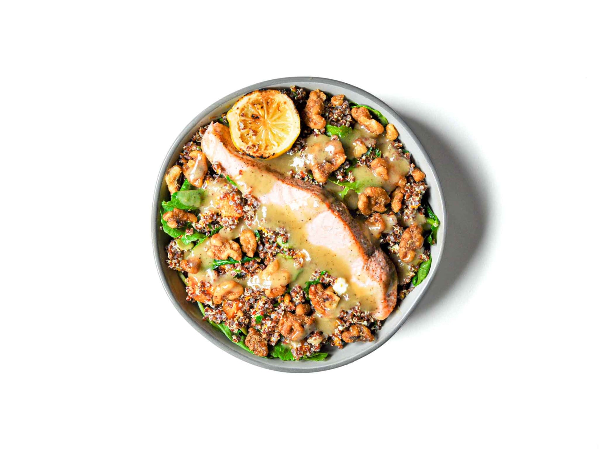 Buddha Bowls' Fall Salmon Bowl showcases perfectly cooked salmon atop a bed of fluffy quinoa, paired with roasted butternut squash and crunchy pumpkin seeds. This hearty and nutritious bowl brings together rich, autumnal flavors for a balanced and satisfying meal.