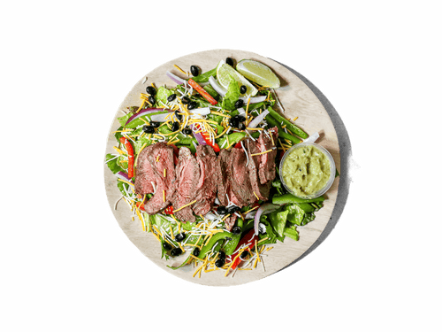 Perfectly seasoned steak strips atop a bed of fresh greens, complemented by zesty avocado tomatillo crema. This flavorful dish delivers a vibrant Tex-Mex twist, perfect for a wholesome and delicious meal.