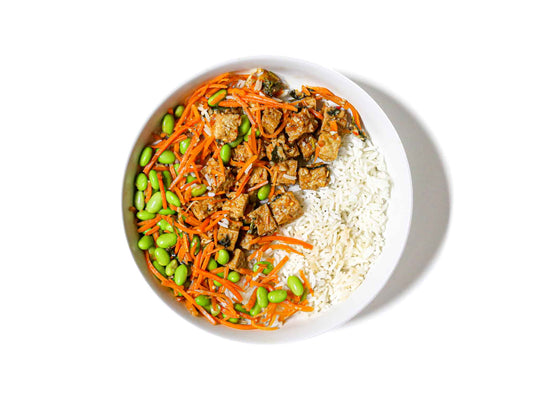 Buddha Bowl's Minted Tofu features flavorful minted tofu served over steamed coconut rice, accompanied by fresh carrots and edamame. This dish offers a refreshing and balanced combination of savory, minty, and crunchy flavors, creating a light yet satisfying meal.